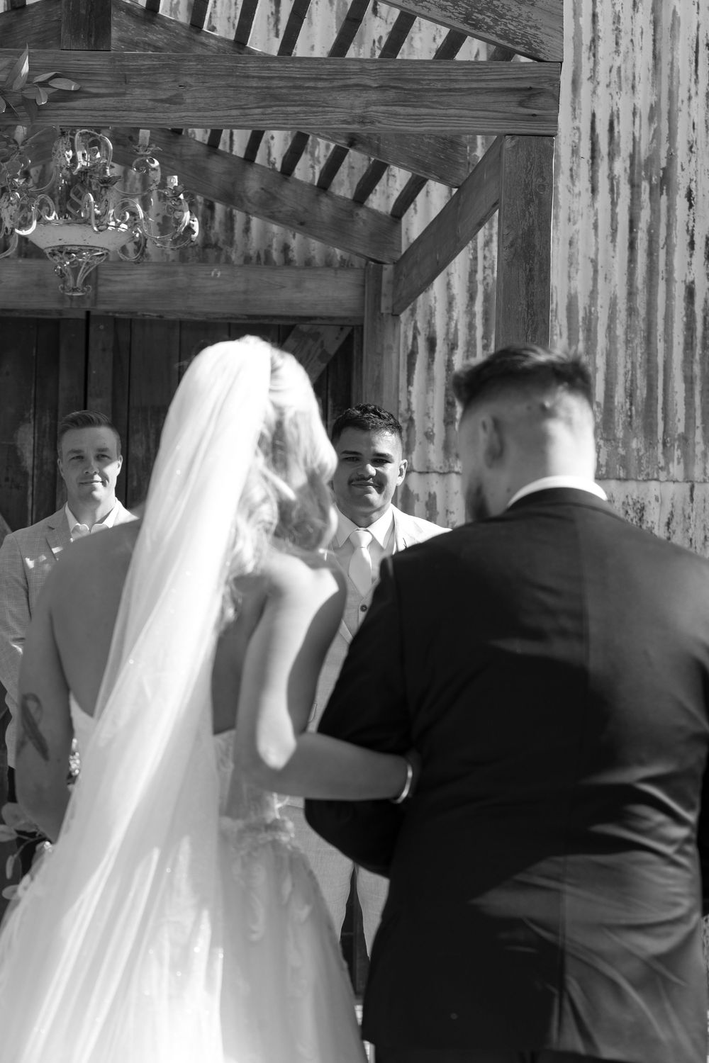 Wedding guests witness a ceremony inside a charming rustic barn with wooden beams.