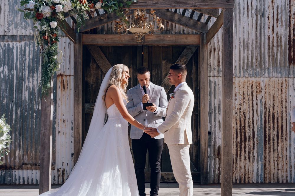 A wedding celebration takes place in a rustic barn decorated with elegant floral arrangements.