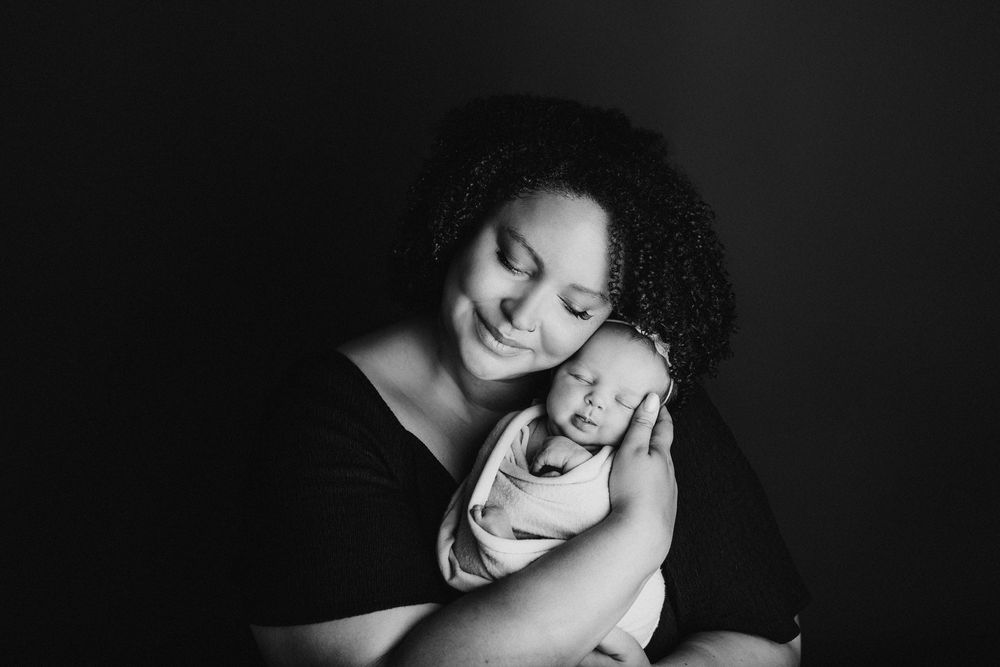 Black and white portrait of mother and baby sharing emotional bonding moment.