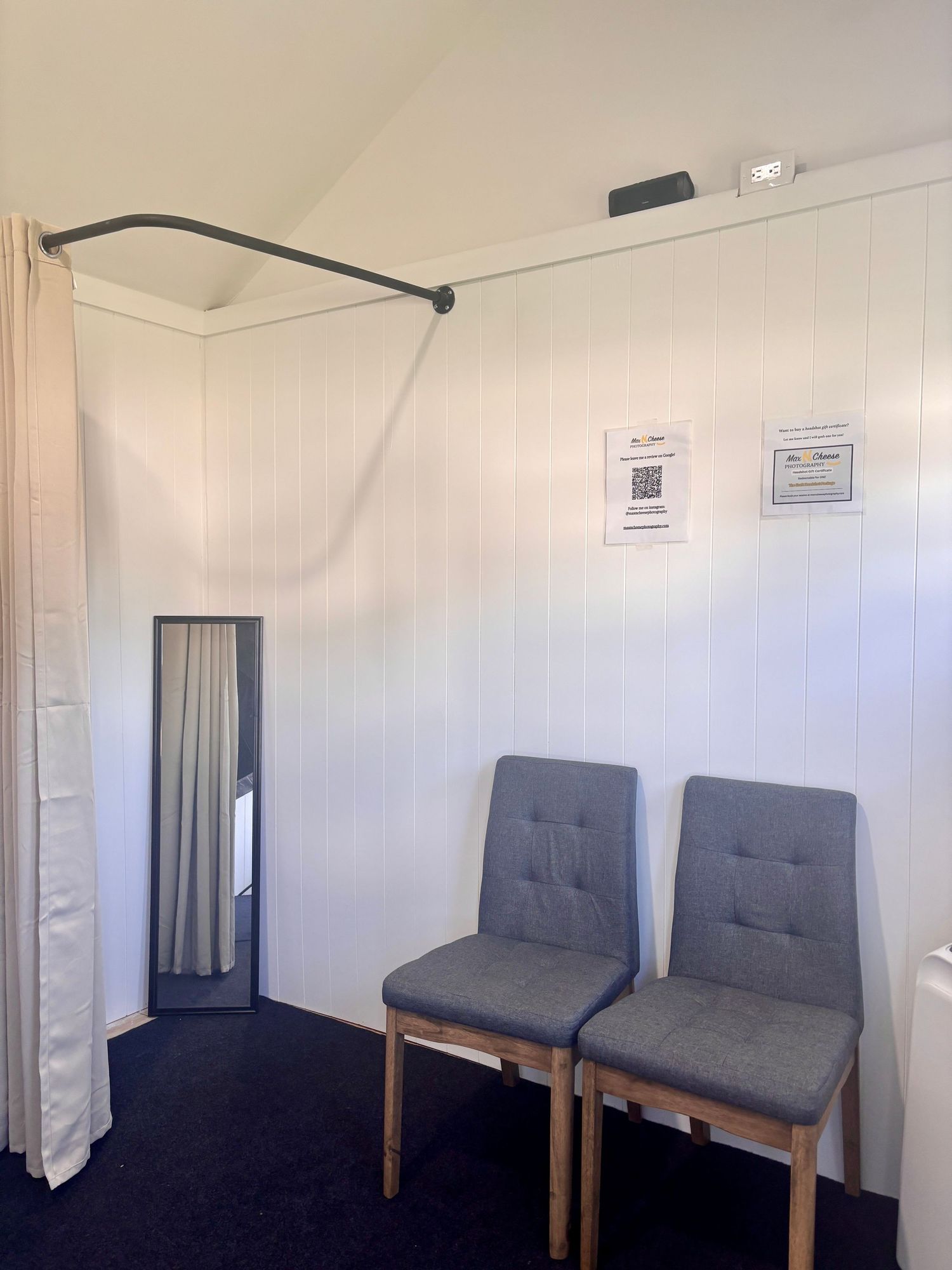 Interior photography studio waiting area with two gray chairs, a mirror, and white shiplap walls.