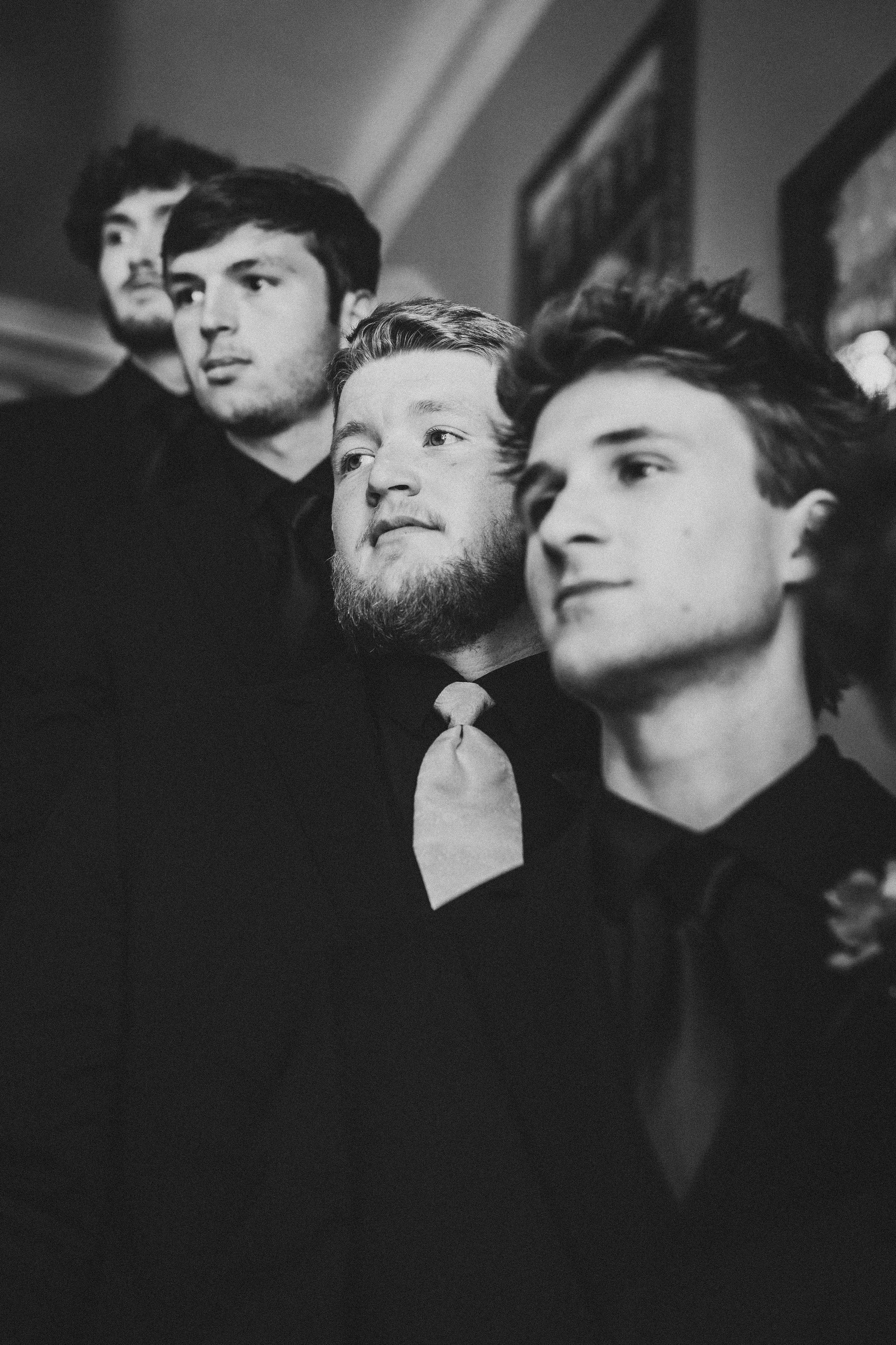 A black and white collage of groom and groomsmen looking upward in contemplation.