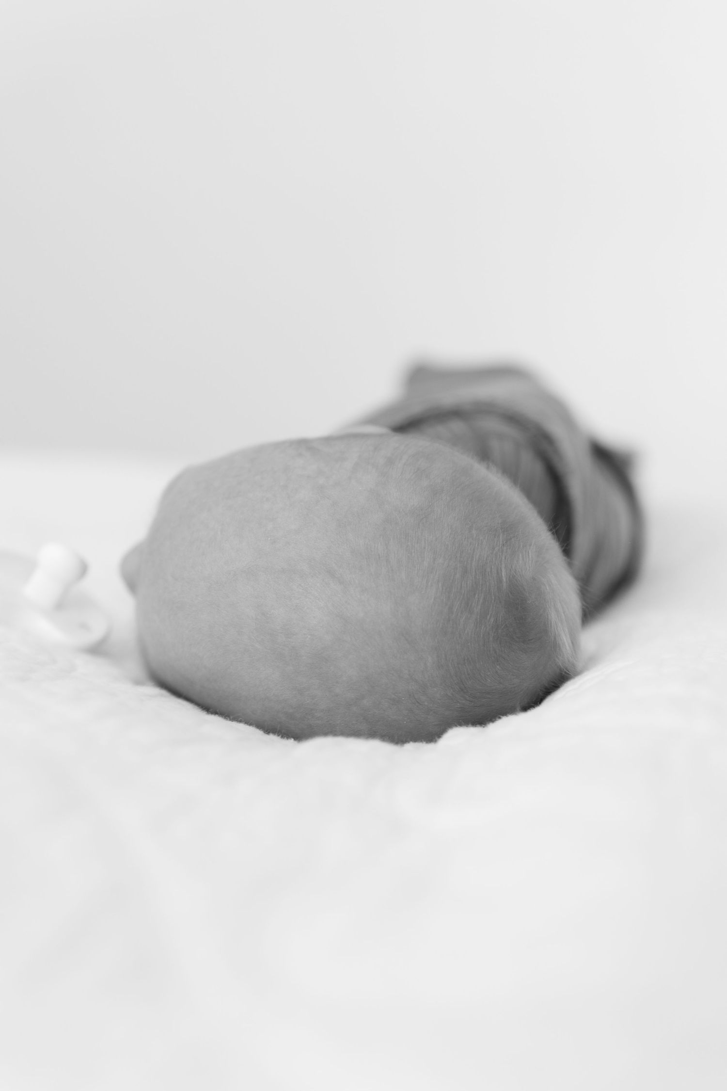 black and white photo of the top of a newborn baby boys head lying on a bed