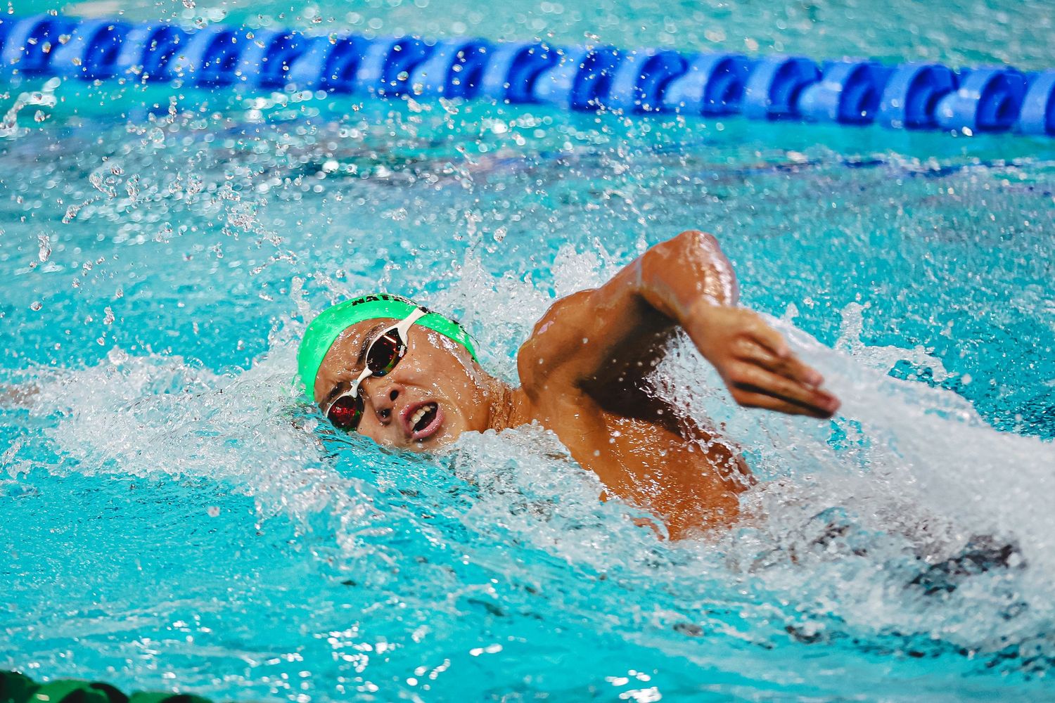Competitive swimmer performing freestyle stroke in blue pool lane during training or competition.