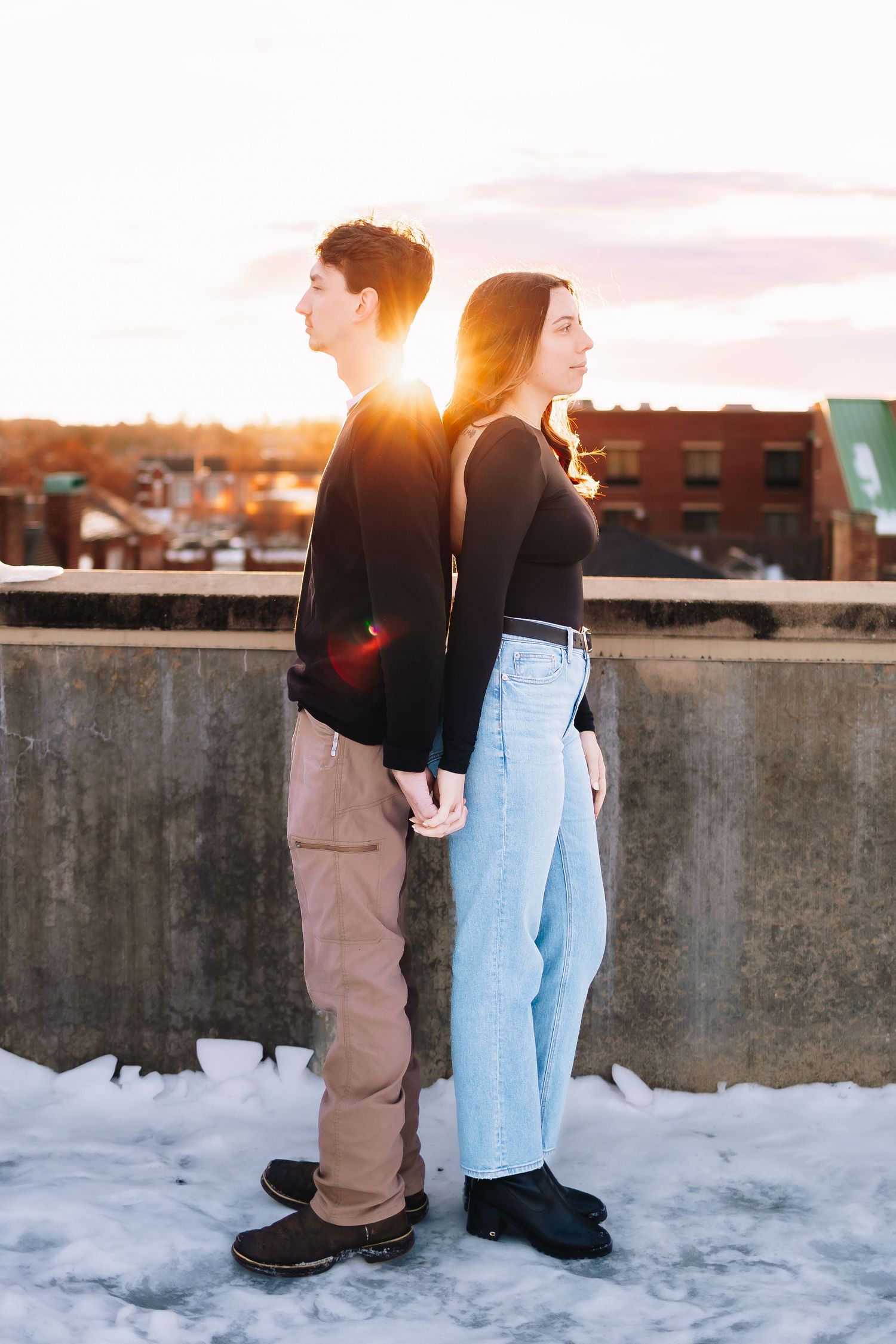 Silhouettes of people standing on a snowy rooftop against a vibrant sunset sky.