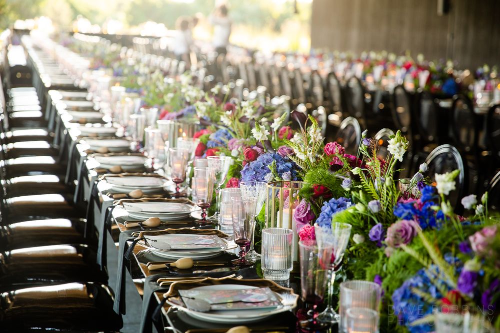 Elegant wedding reception table setting with colorful floral centerpieces and place settings.