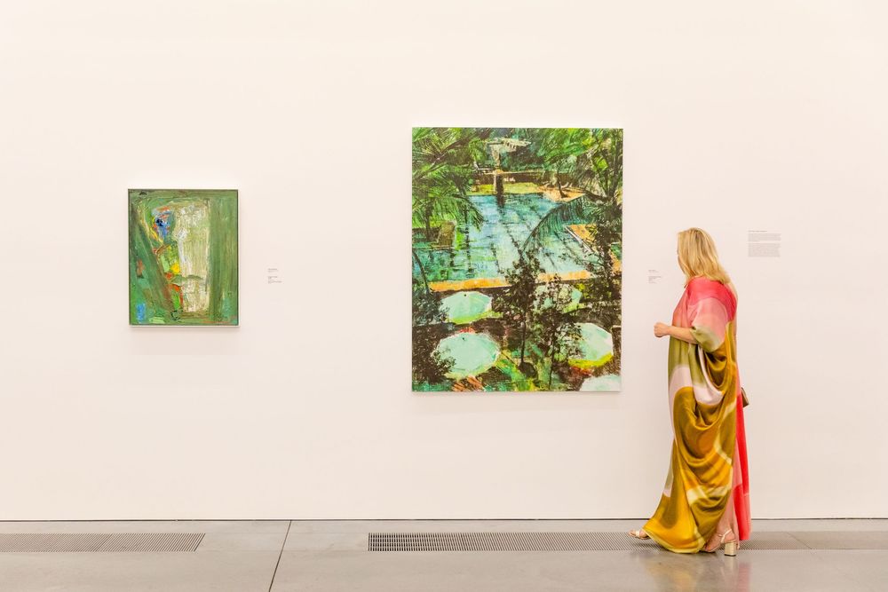 Modern art gallery interior with paintings displayed on white walls.