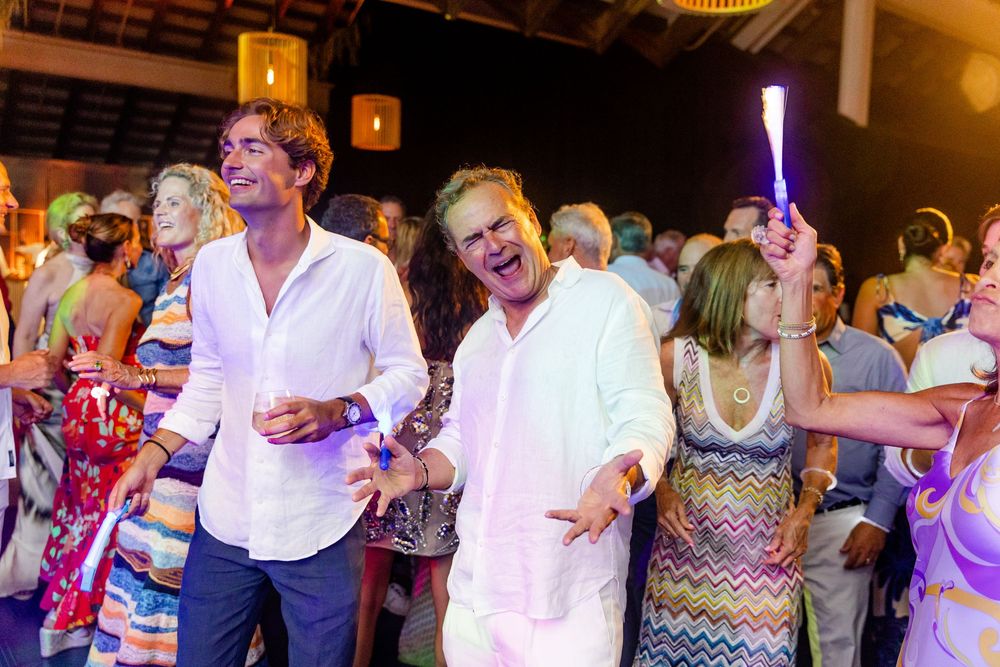 Wedding reception dance floor filled with celebrating guests under warm lighting.