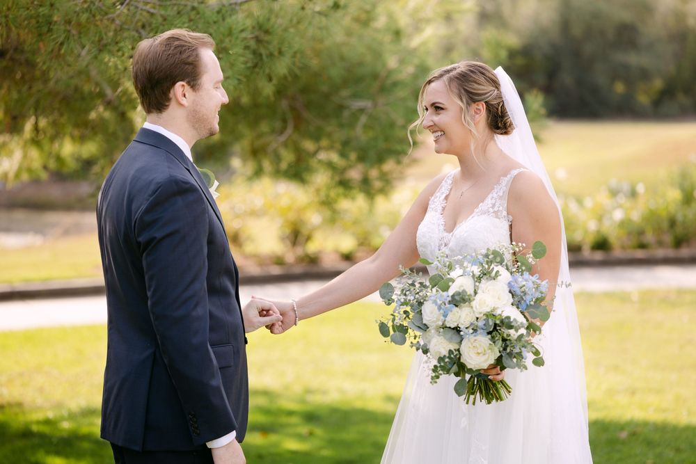 Bride and groom share tender moments together during outdoor wedding photo session in golden sunlit field.