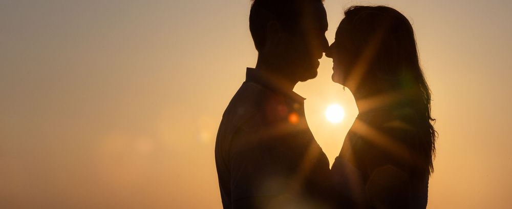 Four silhouettes walking together against a warm sunset sky create a dramatic backlit scene.