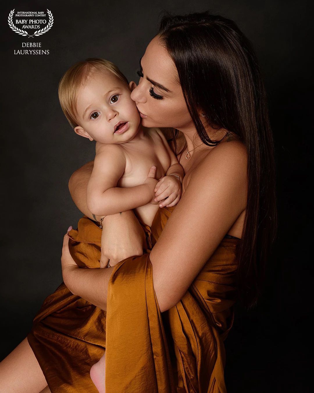 Intimate family portrait in warm earth tones against dark background.