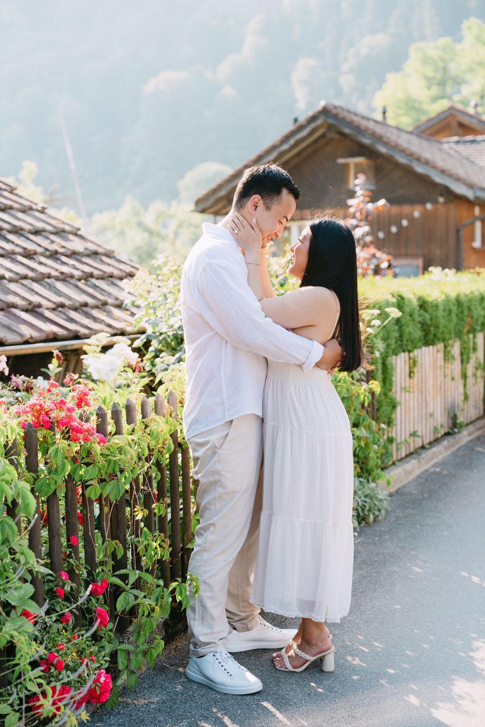 A romantic scene with two people embracing by a rustic chalet with blooming flowers in the Swiss mountains.