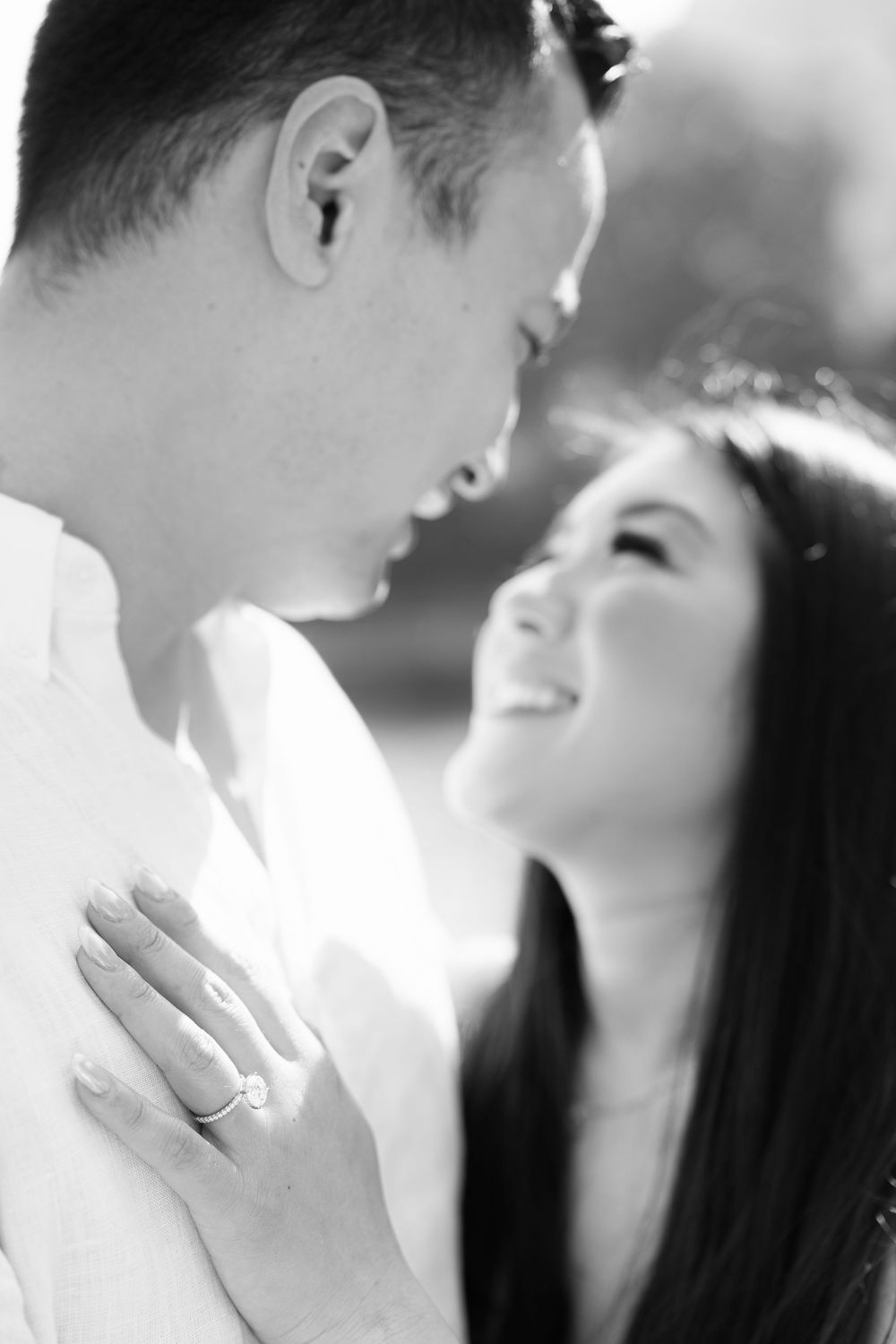 Black and white close-up photos of a romantic embrace near a lake.