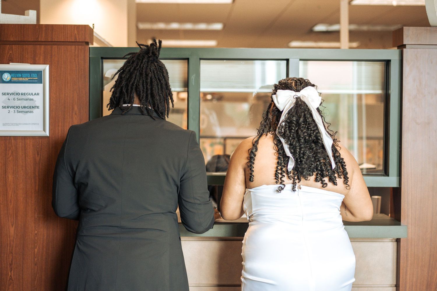 Three people at a service counter or reception area consult with staff members in a professional office setting.