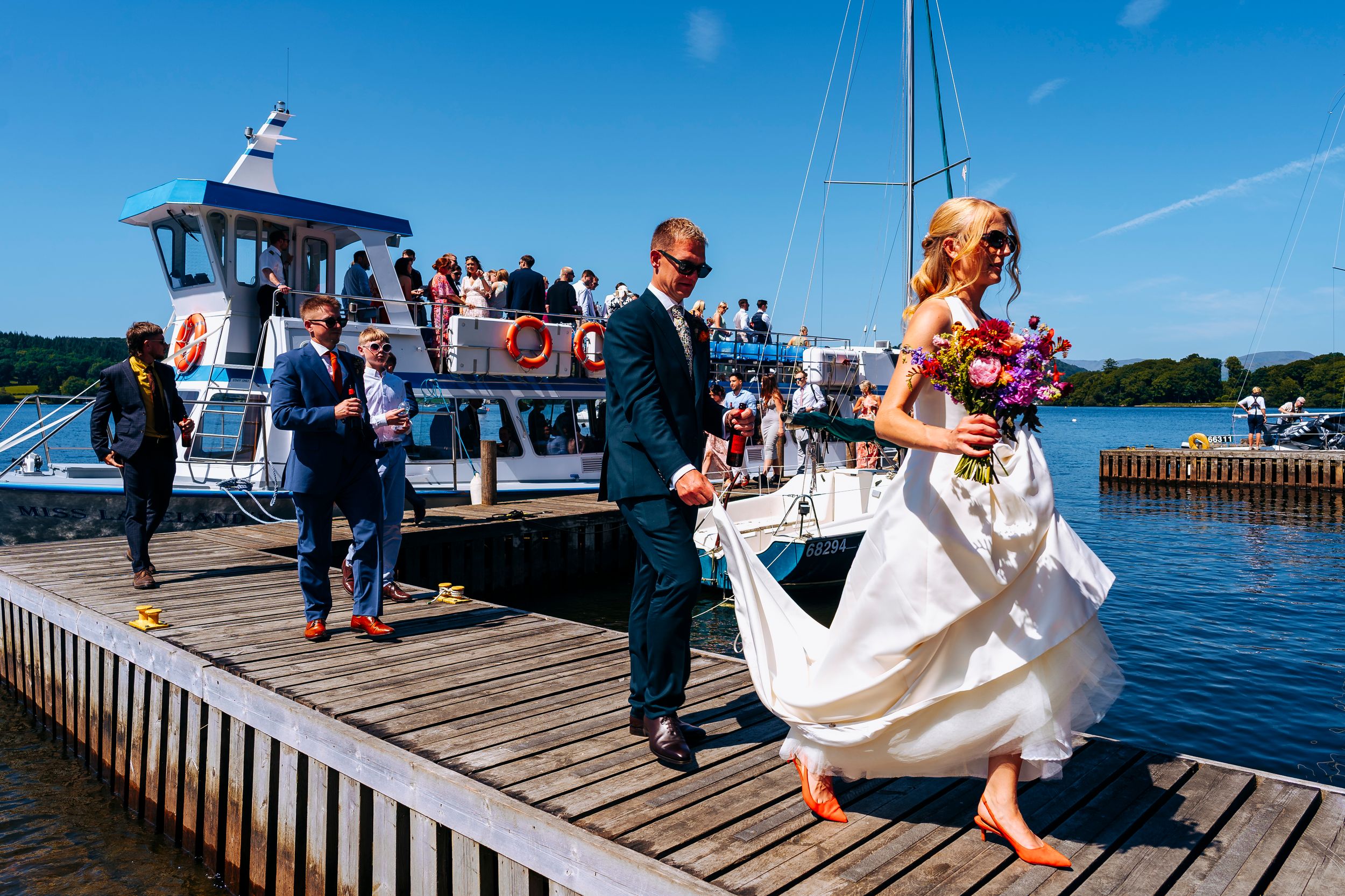 Bride and Groom disembarking windermere cruiser on the way to their wedding reception, guests join them in walking along the jetty