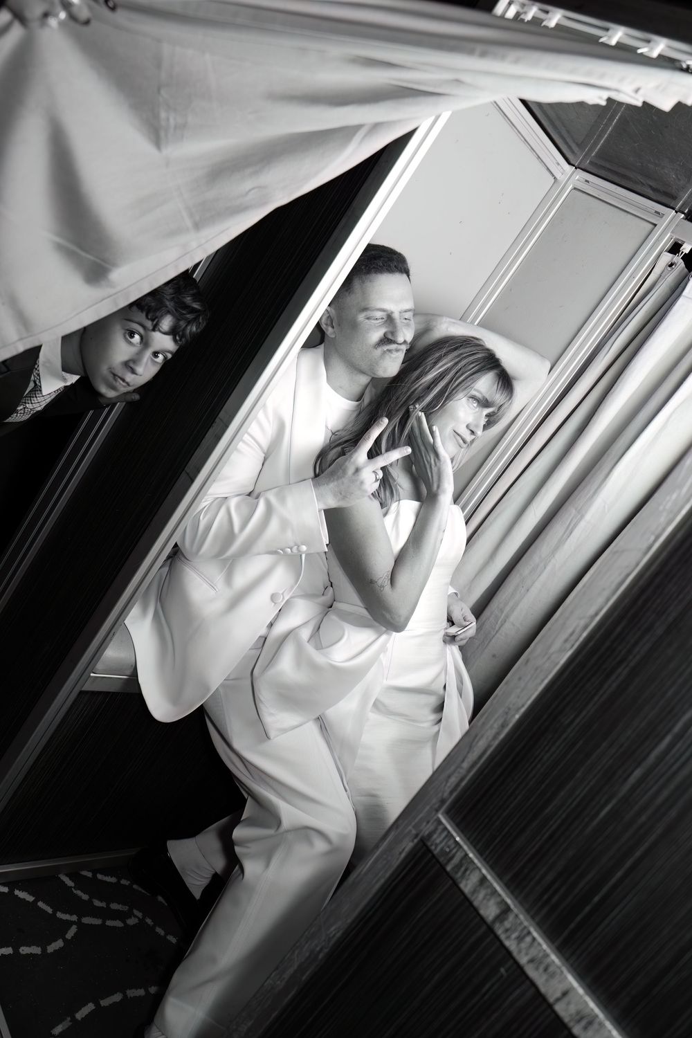 A couple in white attire poses together against a mirrored surface.