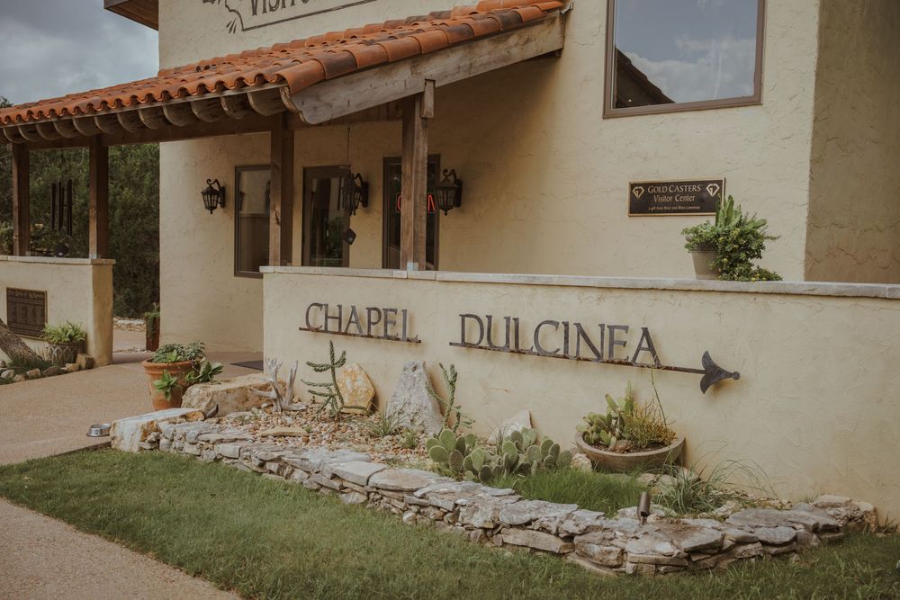 Spanish-style mission building with white walls and rustic signage.