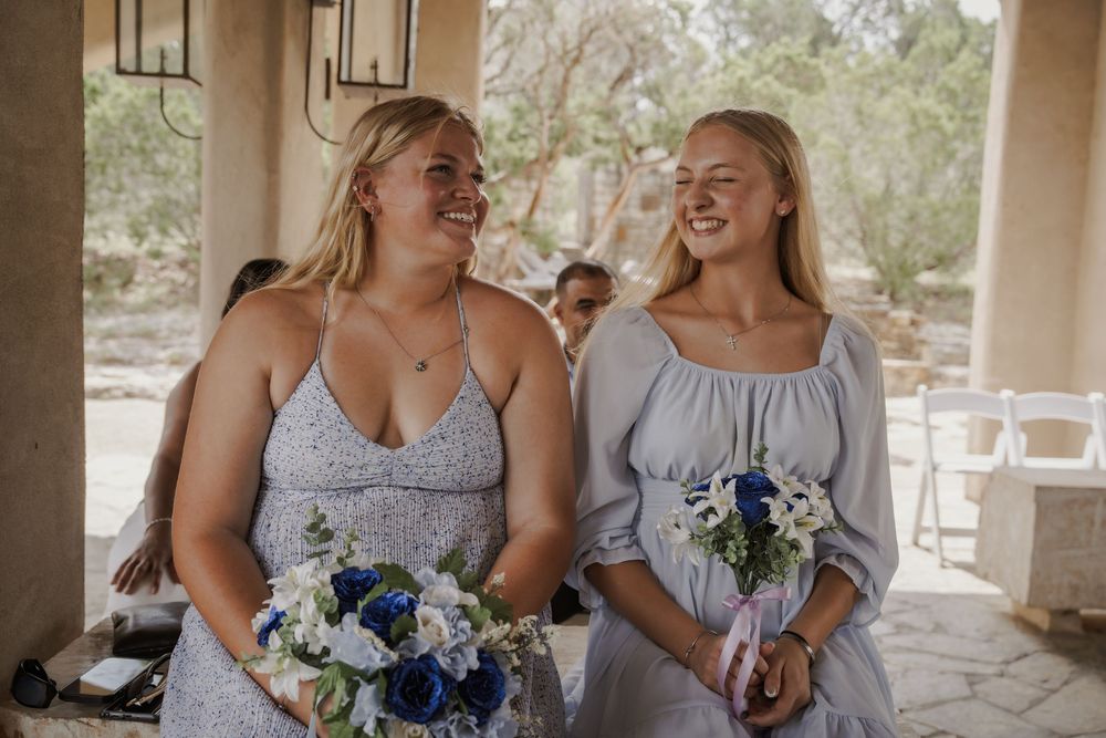 Bridesmaids in light blue dresses share a joyful moment during wedding festivities.