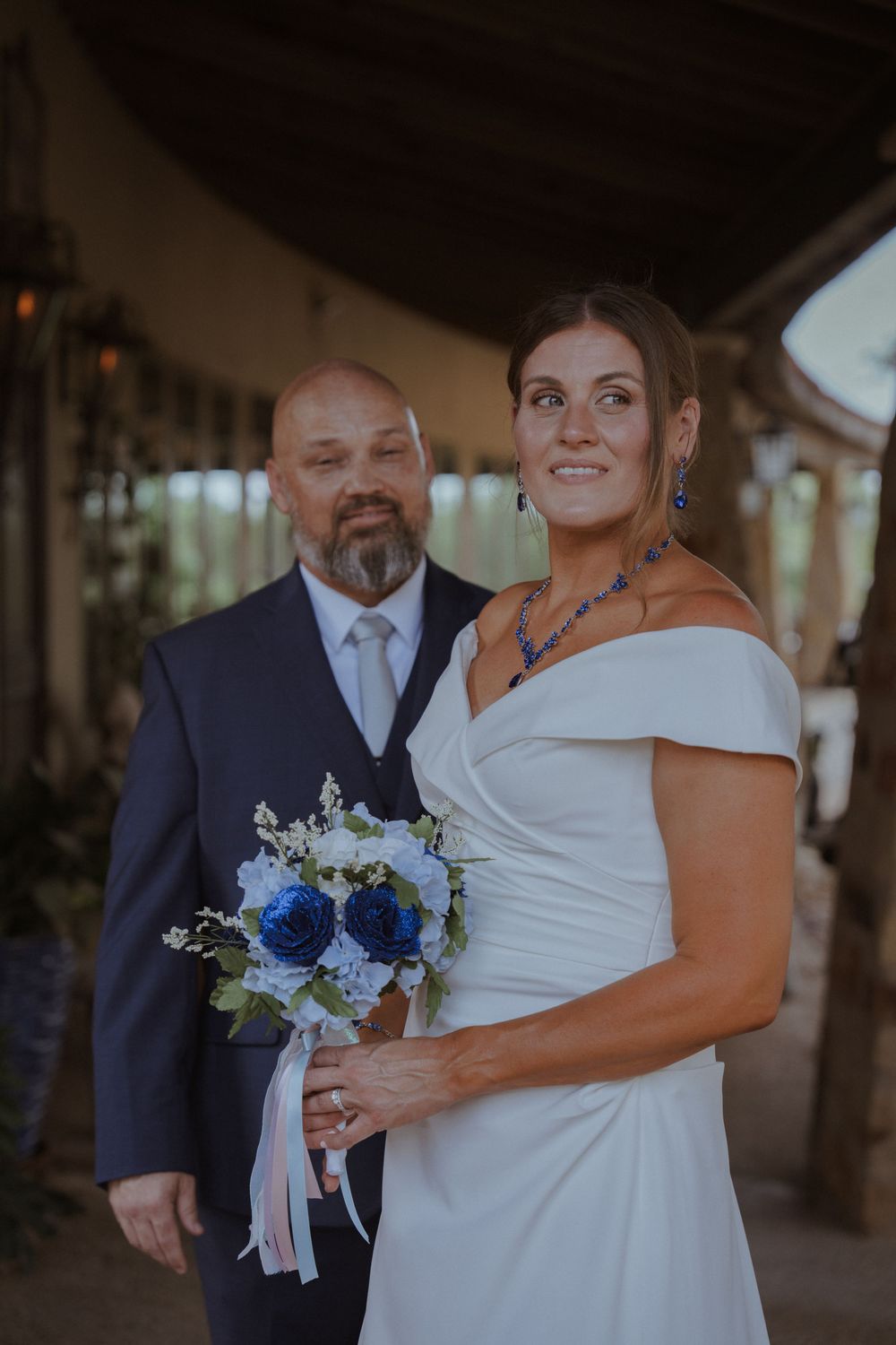 Wedding couple shares tender moment under covered outdoor venue with natural lighting.
