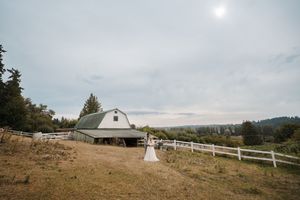 A romantic outdoor wedding ceremony setup with white chairs on a hilltop overlooking a scenic mountain landscape.