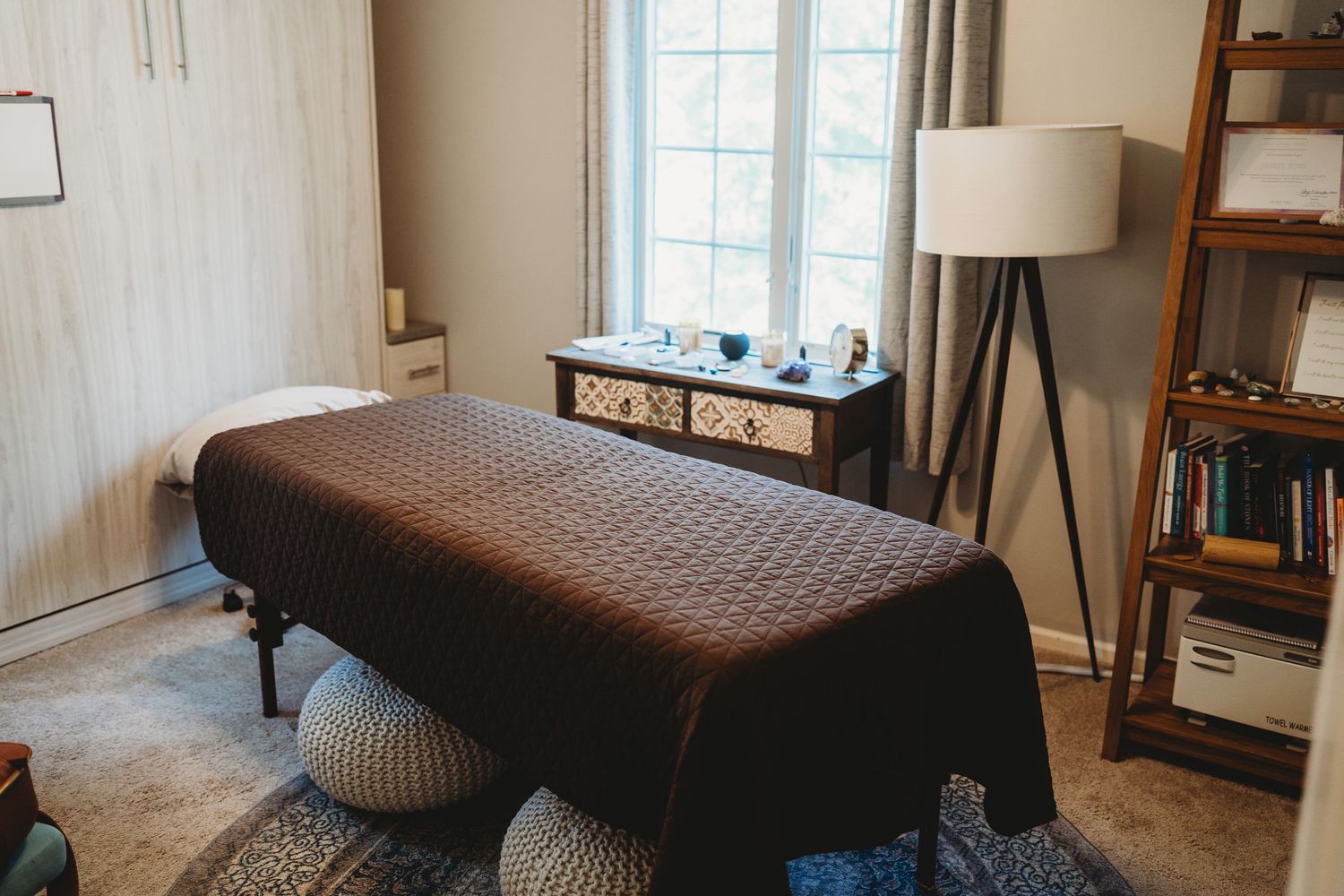 A brown leather tufted chaise lounge chair sits elegantly in a bright corner room with natural lighting.