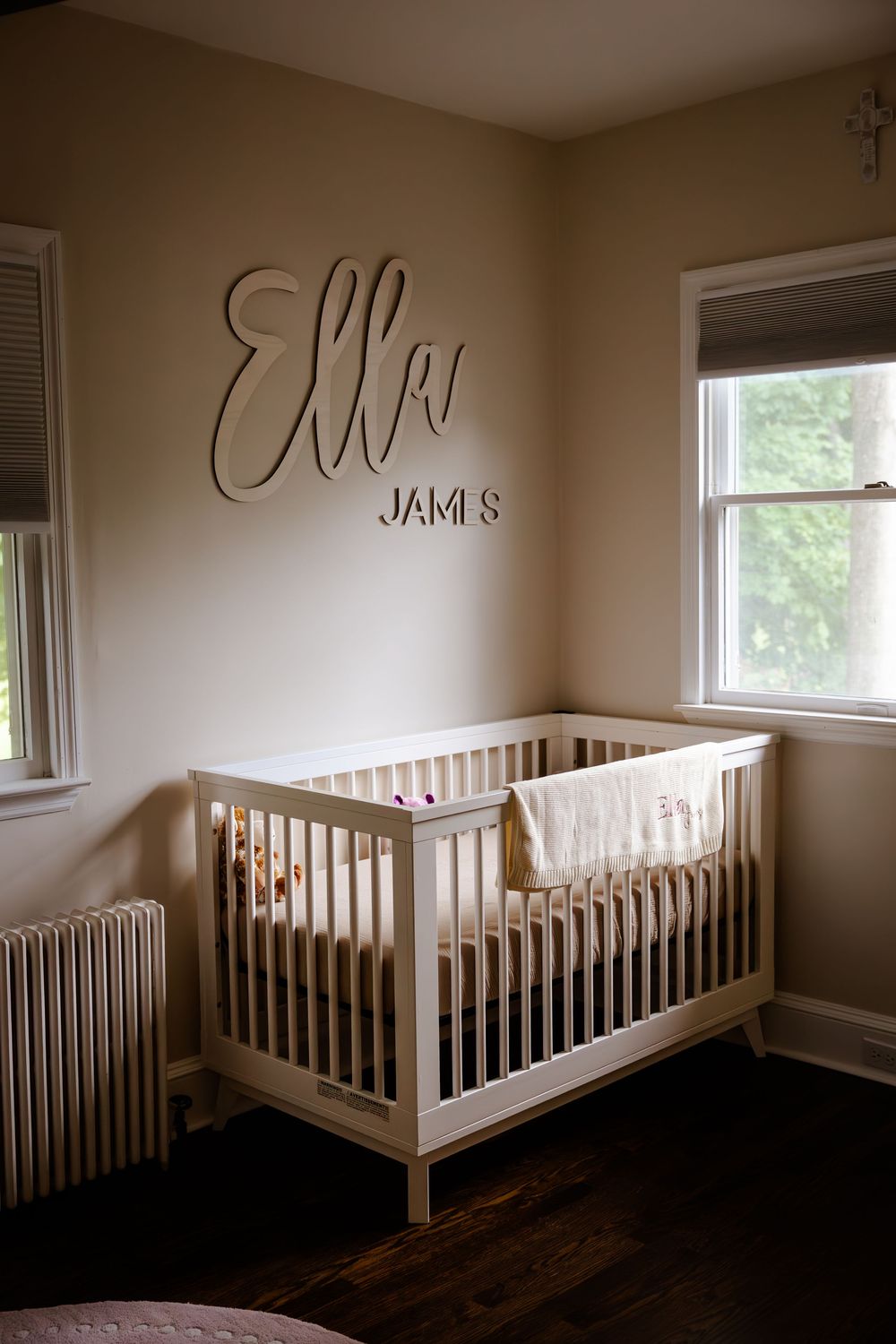 Modern nursery room with multiple white cribs and windows displaying decorative wall text.
