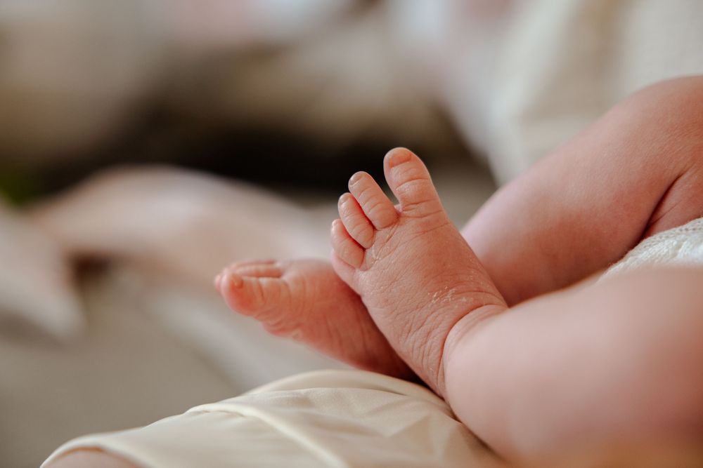 Close-up view of tiny newborn baby feet on soft white fabric.