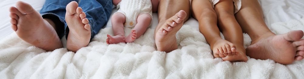 Close-up of tiny baby feet and toes on white textured blanket.