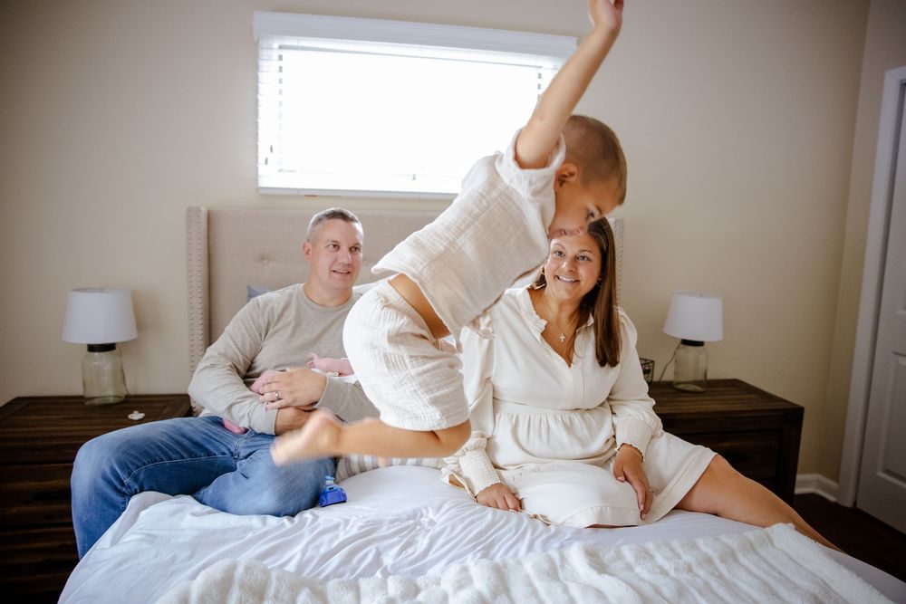 Family lifestyle moment on white bedding in natural window light.