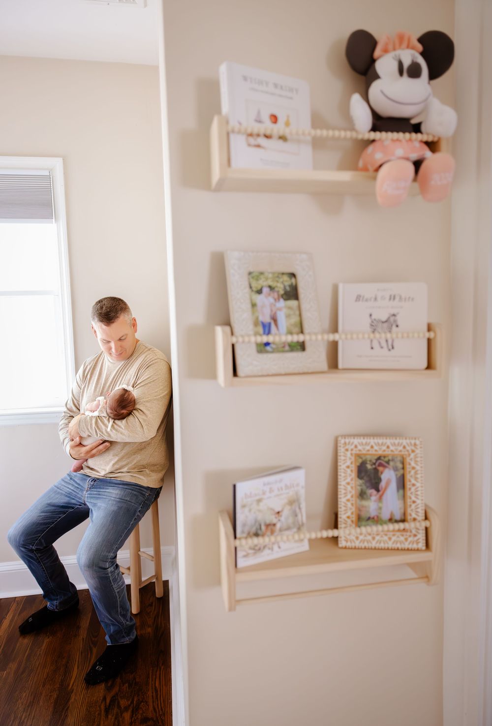 Nursery wall decorated with floating shelves displaying artwork, photos and stuffed Mickey Mouse plush toys.