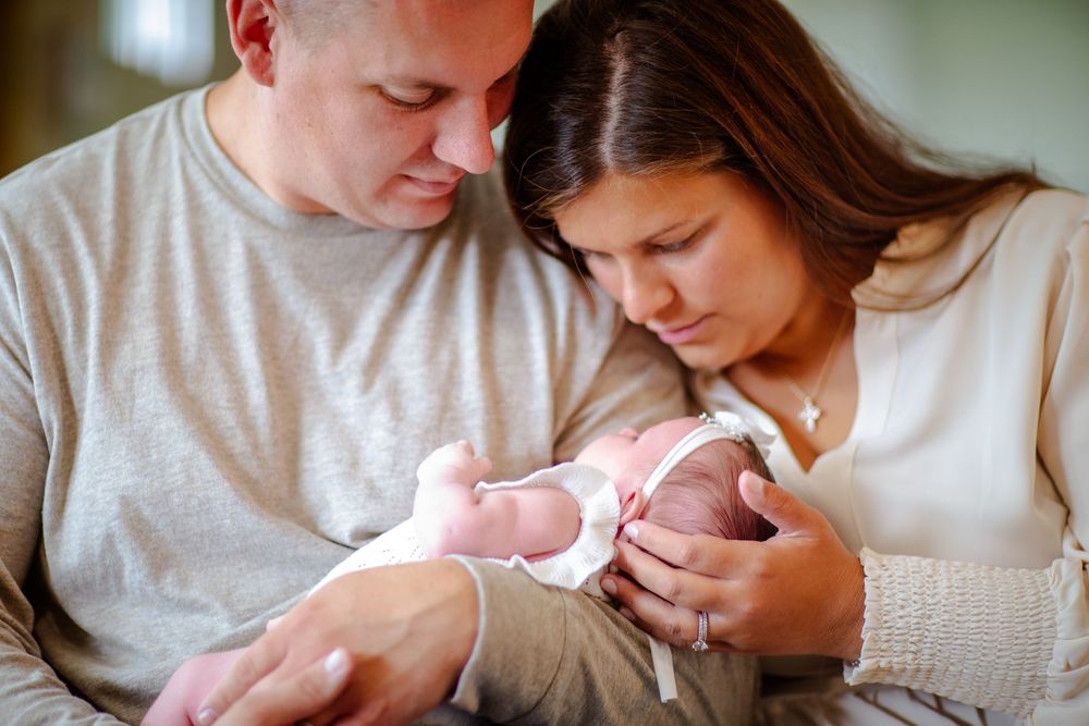 Intimate family moment captured in soft natural light while holding a newborn baby.