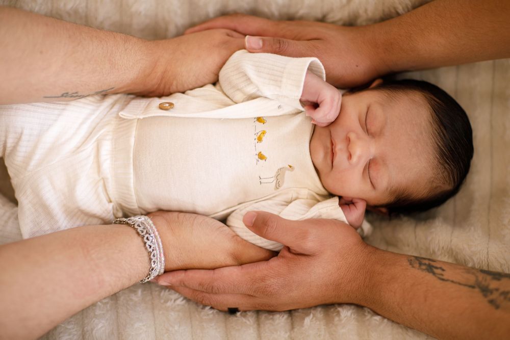 Newborn baby sleeping peacefully on white blanket during photo session.