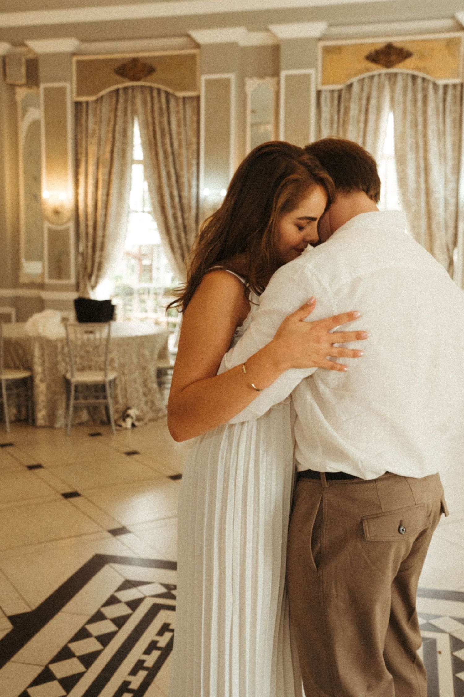 Couple dancing in an elegant room with vintage decor and natural light.