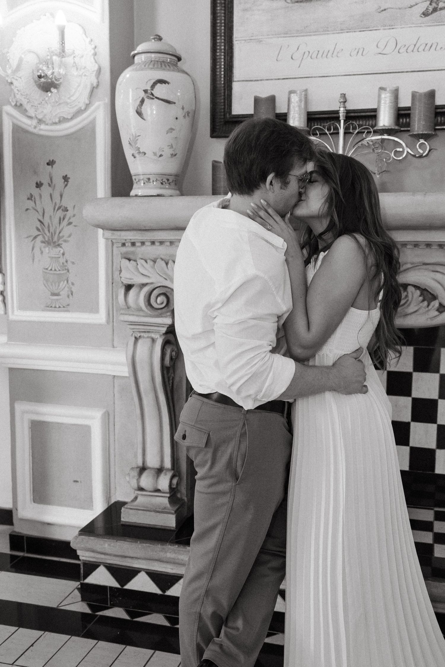 Two people embrace in a vintage-styled room with decorative wall panels.