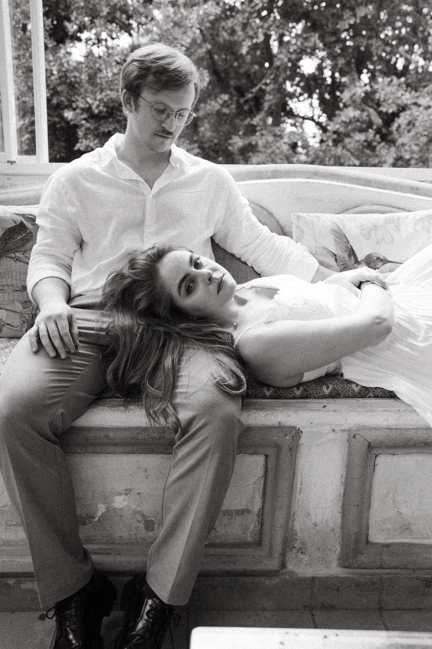 Black and white photo series of a couple resting on a stone ledge outdoors.