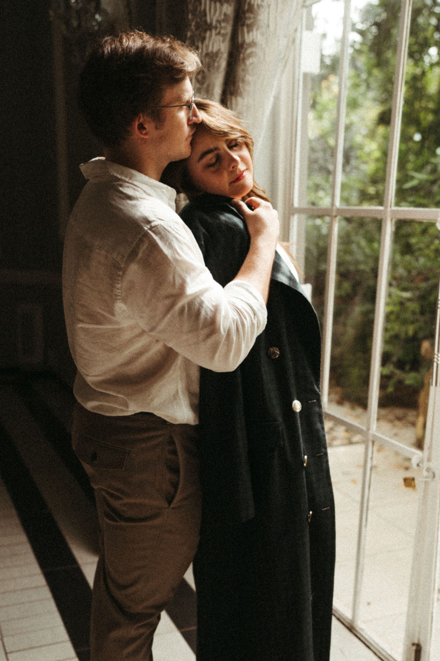 A sequence of black and white photos showing tender moments by a sunlit window.