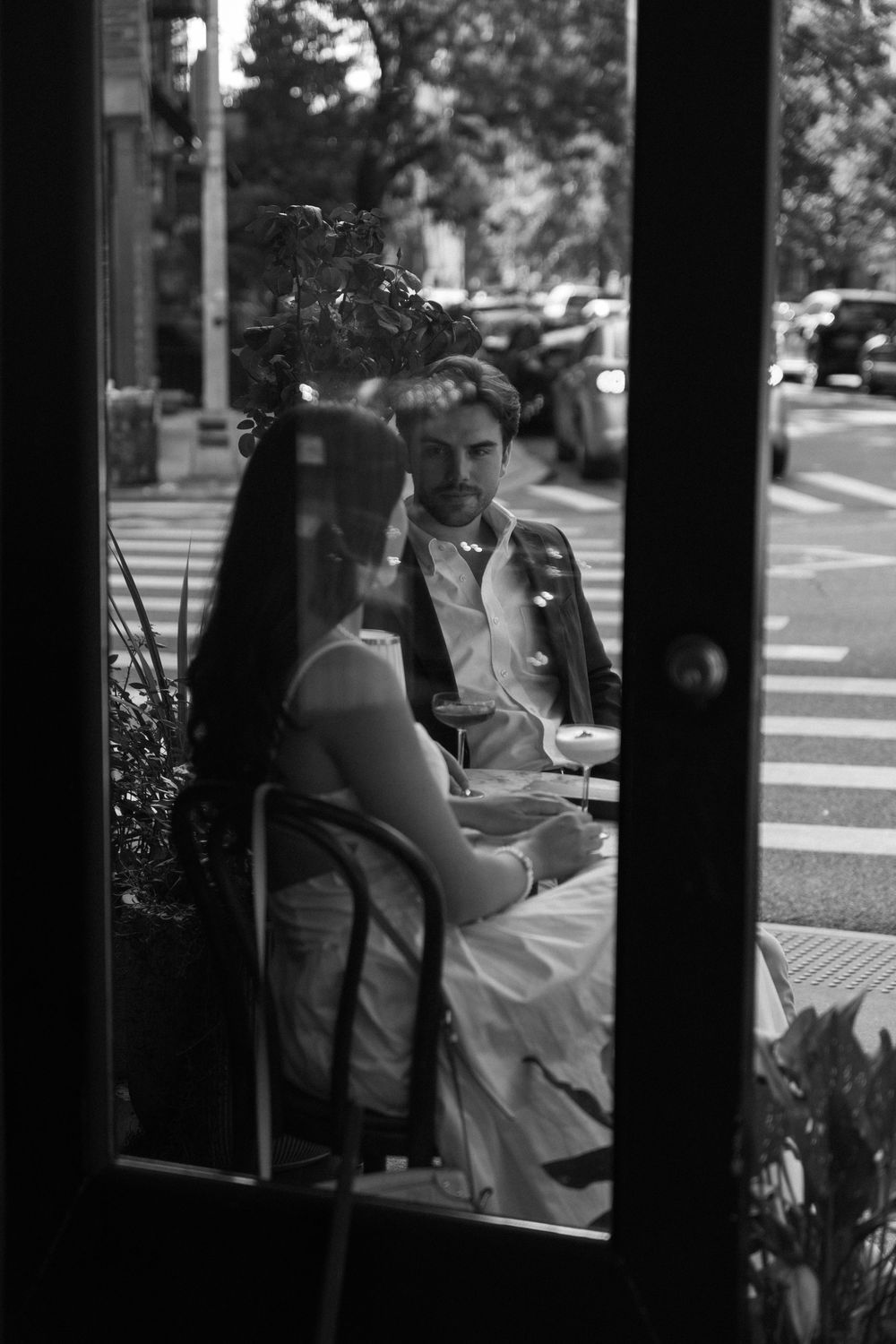 A black and white photo shows people seated at a window in what appears to be a cafe or restaurant.