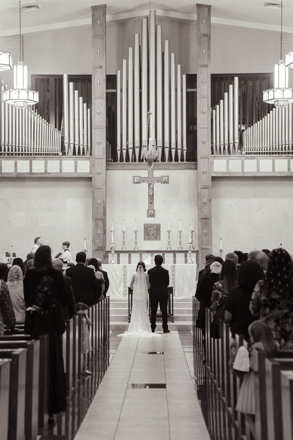 A black and white church wedding ceremony showing guests seated in pews with an organ pipe display visible in the background.