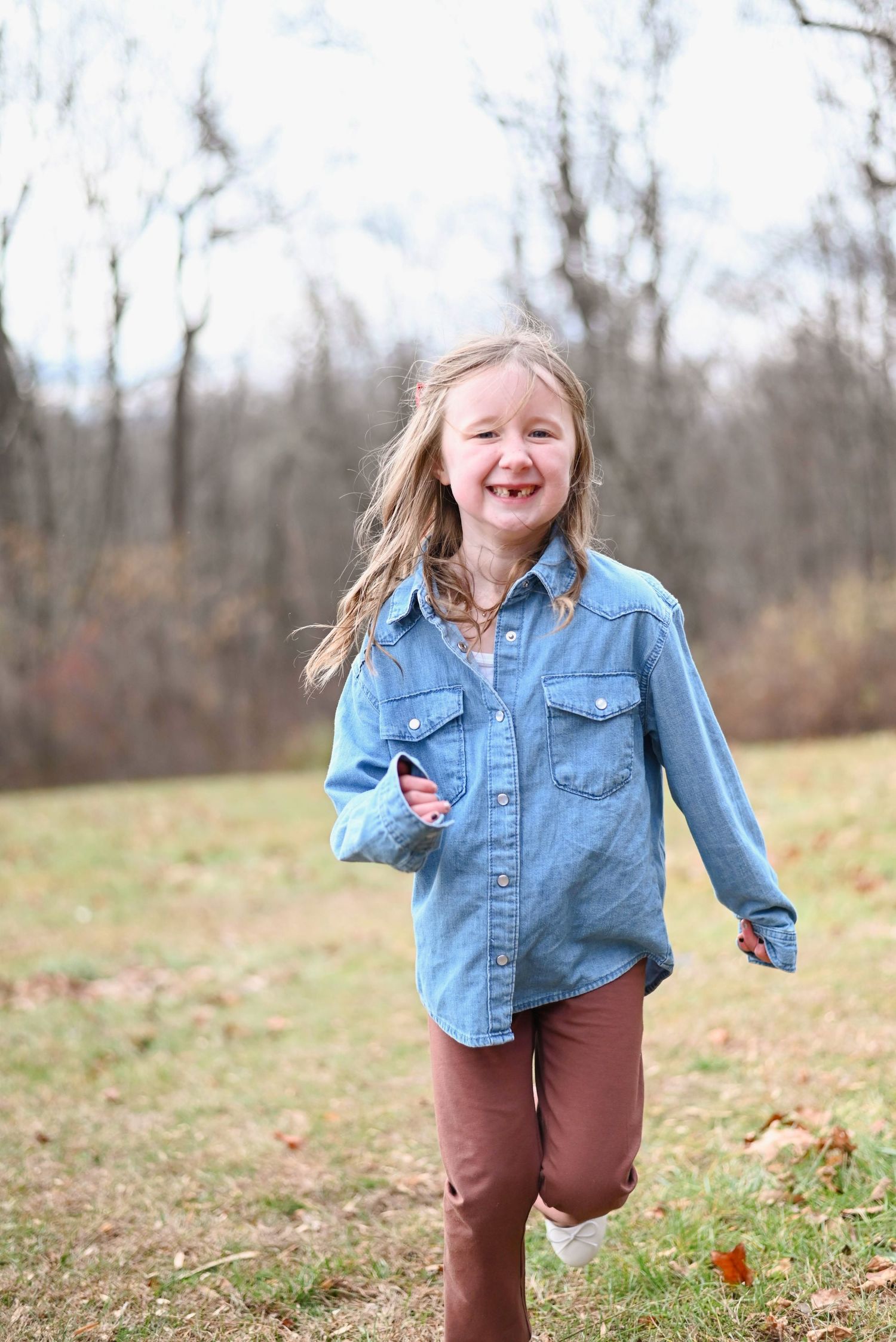 Joyful movement captured outdoors on a fall day wearing denim and brown pants.