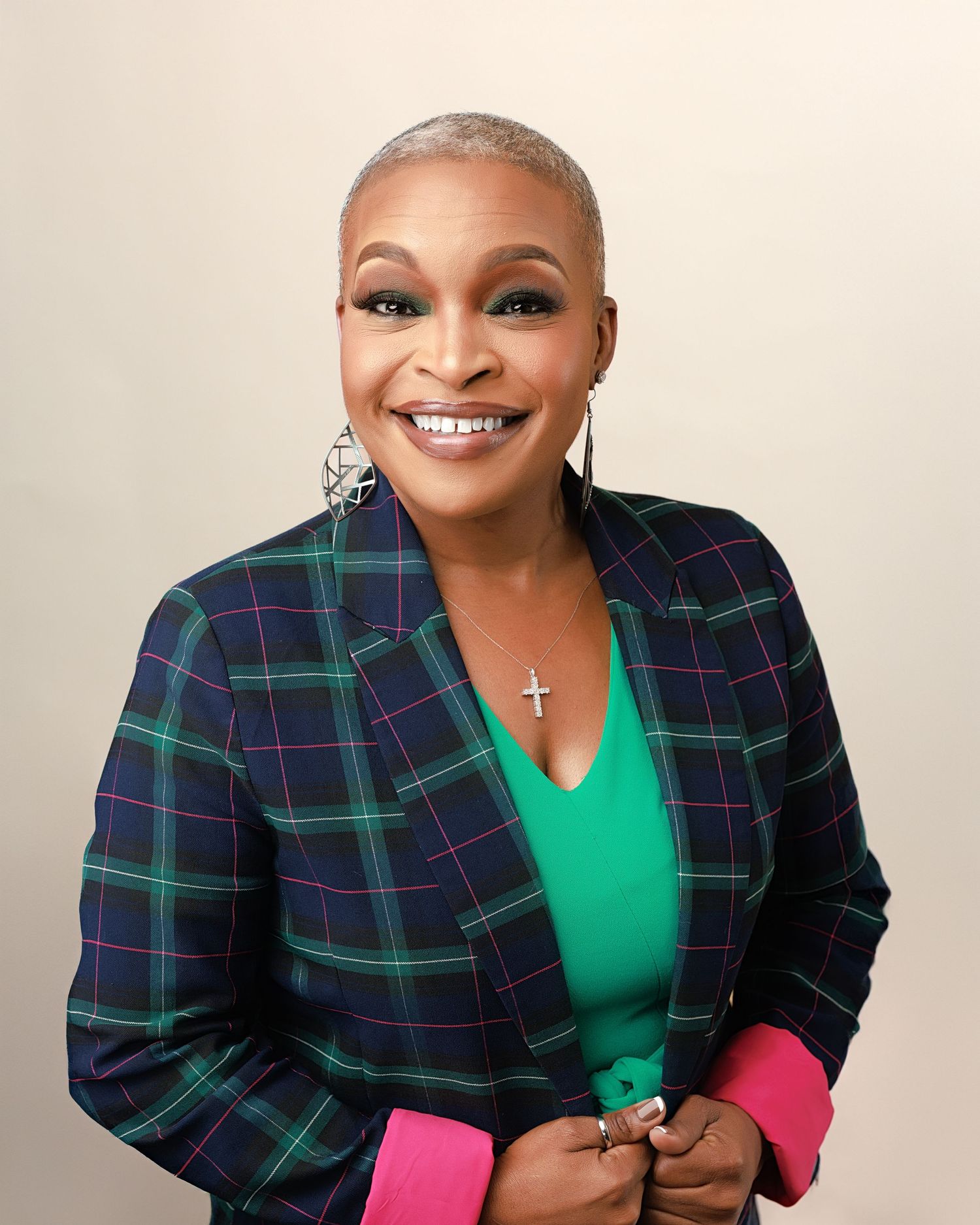 A person in a navy and green plaid blazer with a bright green top and pink bottom poses in multiple expressions.