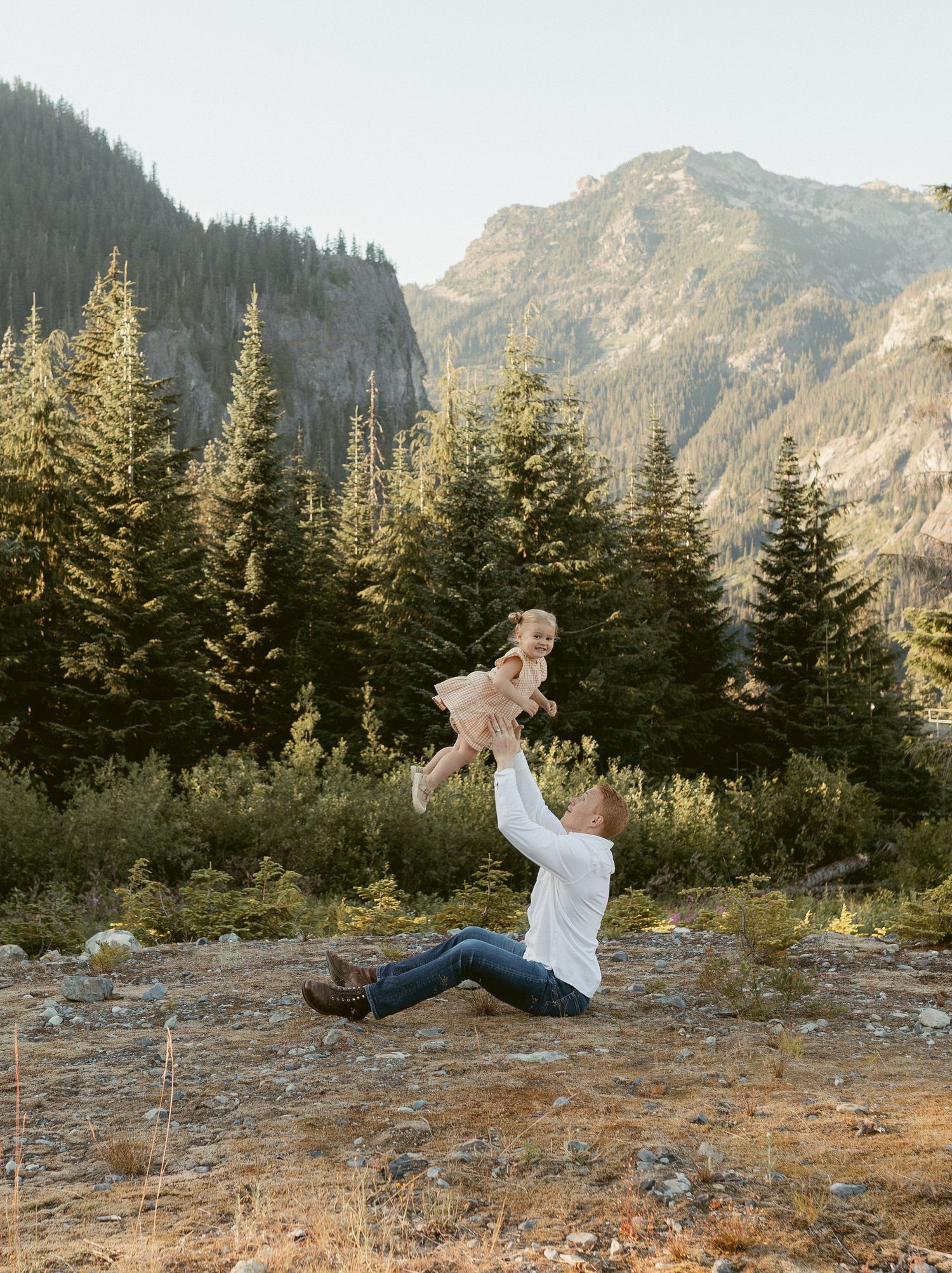 A sequence of four photos shows someone doing a backflip on a mountain ridge with evergreen trees and peaks in the background.