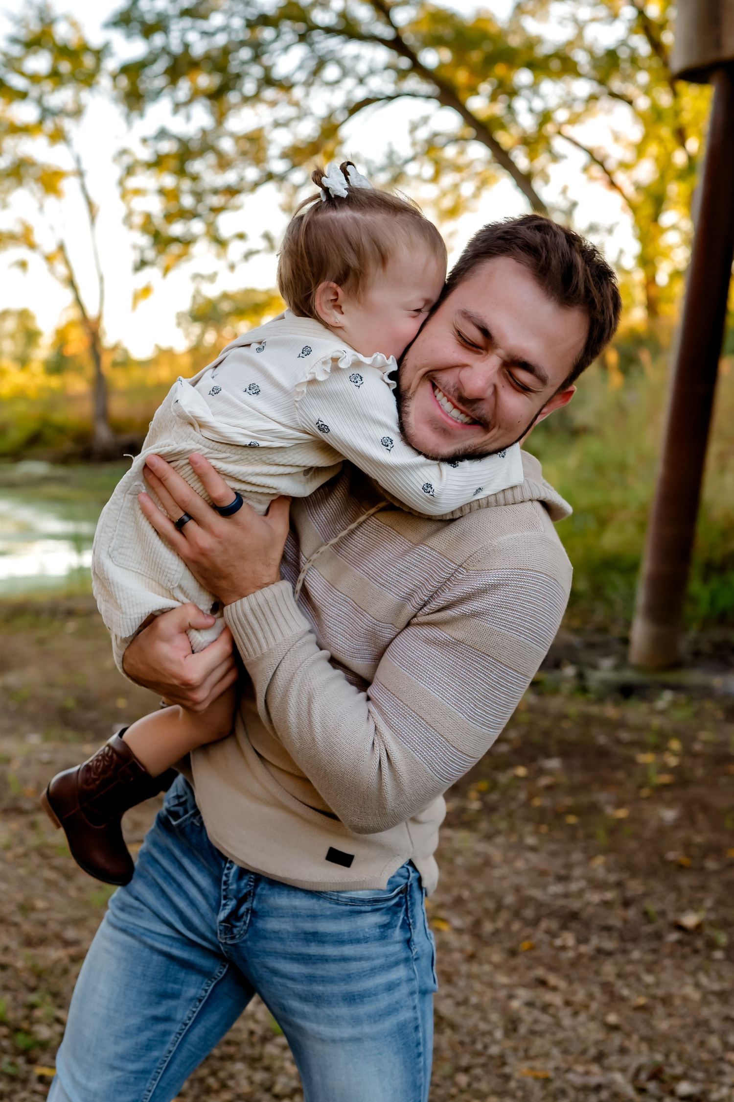 A playful parent and toddler share joyful moments together outdoors during golden hour in a wooded setting.