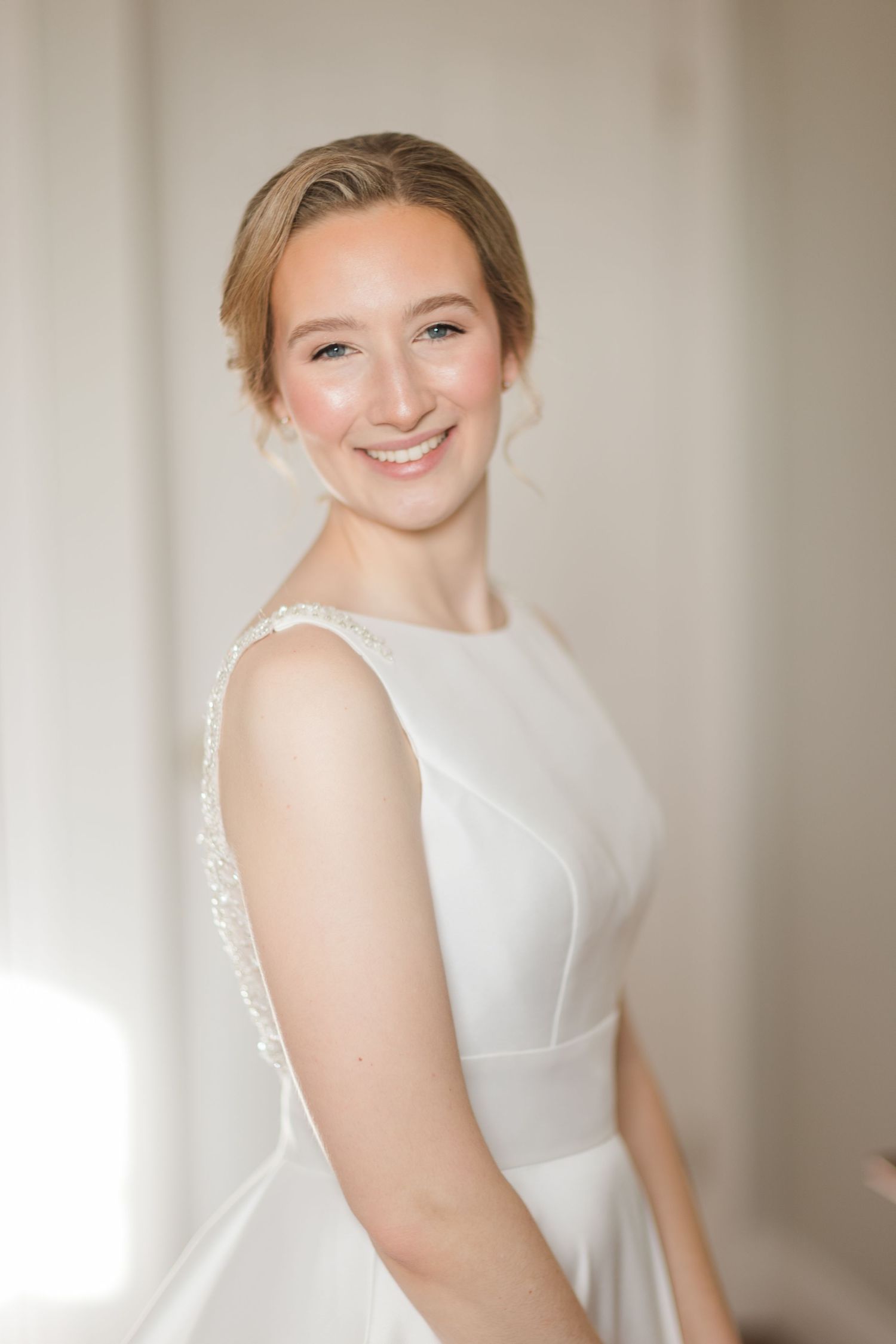 A person wearing a sleeveless white bridal gown poses in front of a light-colored wall in a series of portraits.
