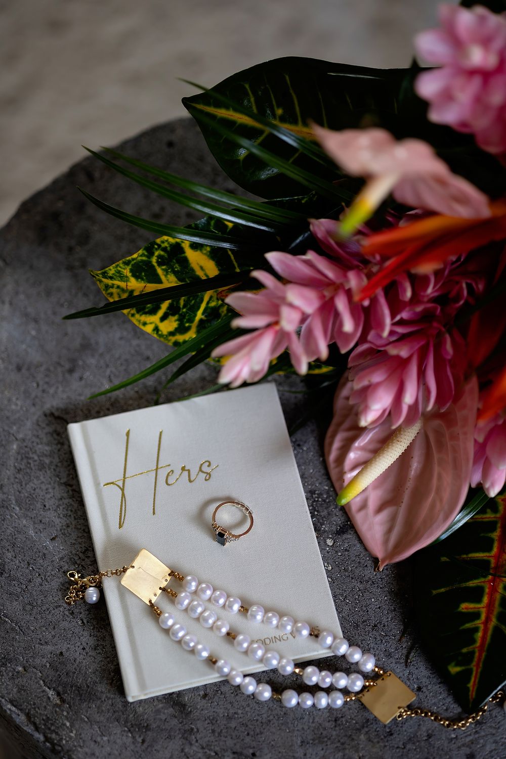 Flat lay of wedding jewelry and vow book with tropical florals at Secrets Moxché Playa del Carmen.