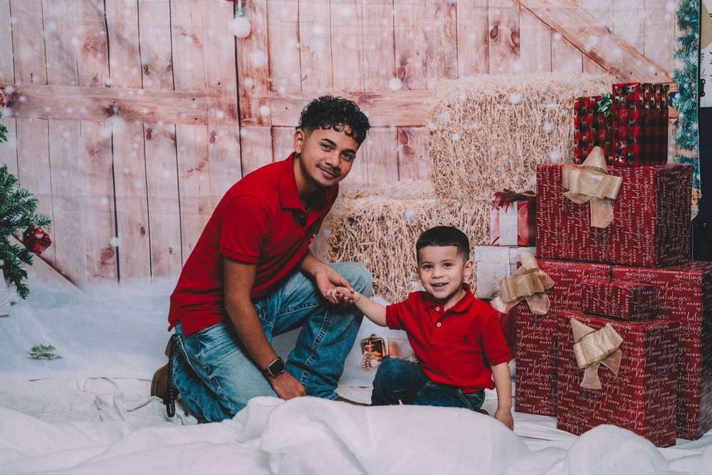 Holiday photo session with red and green decor against rustic wooden backdrop.