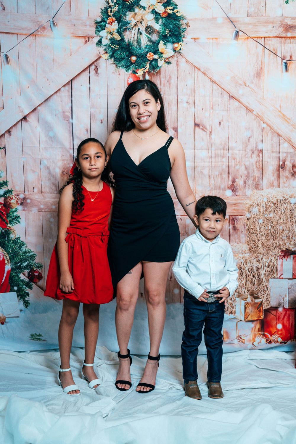 Holiday photo with coordinated black and red outfits against rustic barn door backdrop.