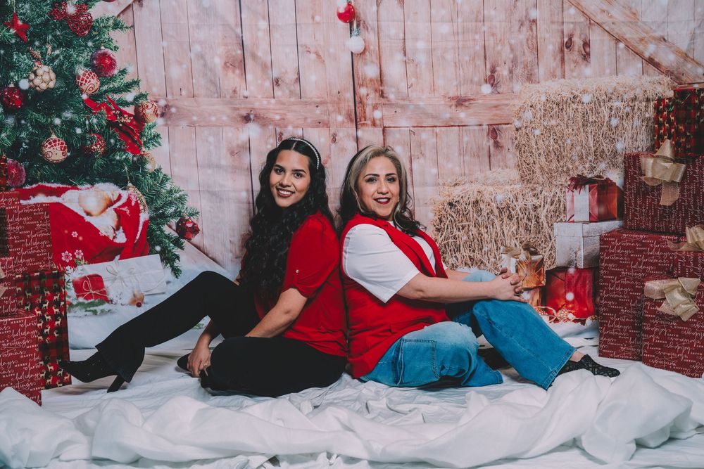 Christmas photo session with people lounging on white floor against festive backdrop.
