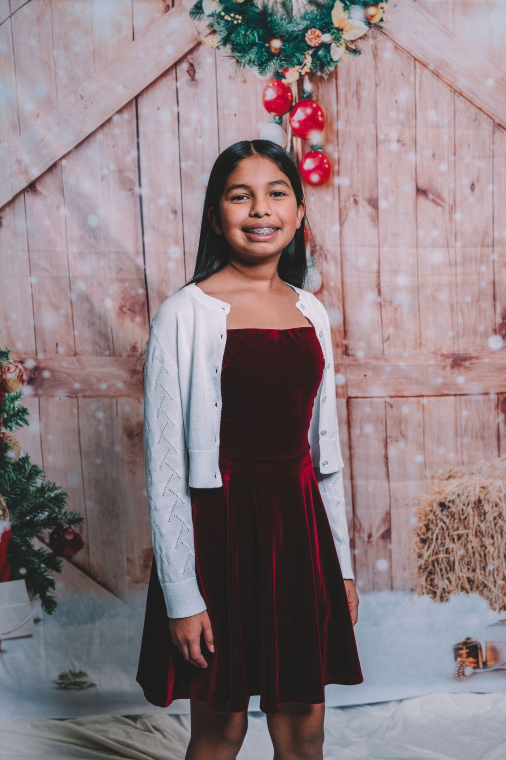 Holiday portraits featuring velvet dress against rustic winter backdrop.