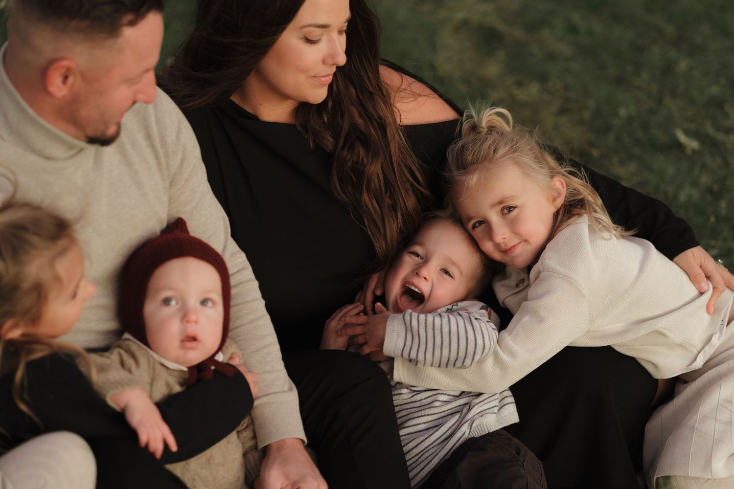 A loving family shares a candid moment together while sitting outdoors in casual attire.