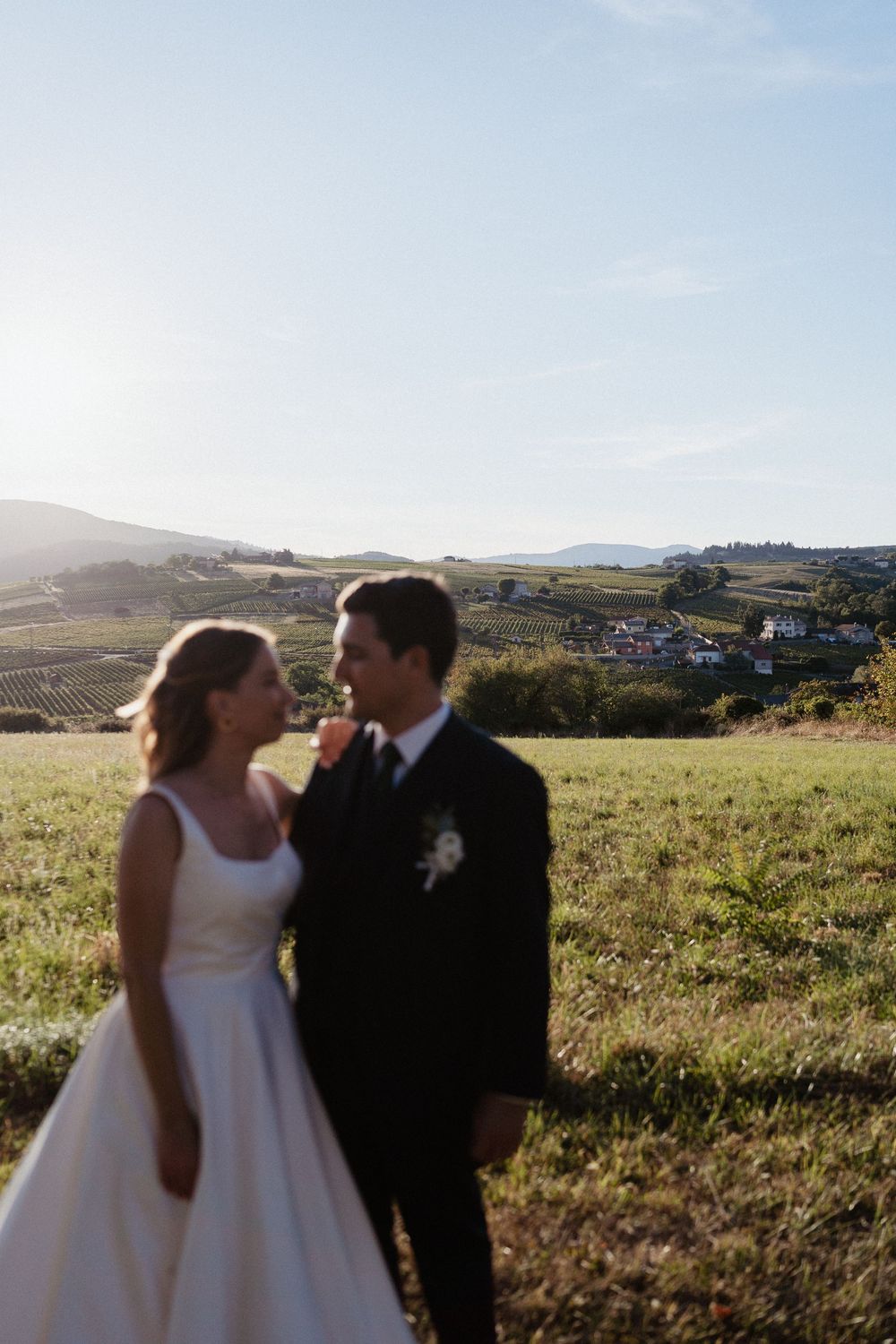 un couple de mariés flou avec le paysage du beaujolais en fond