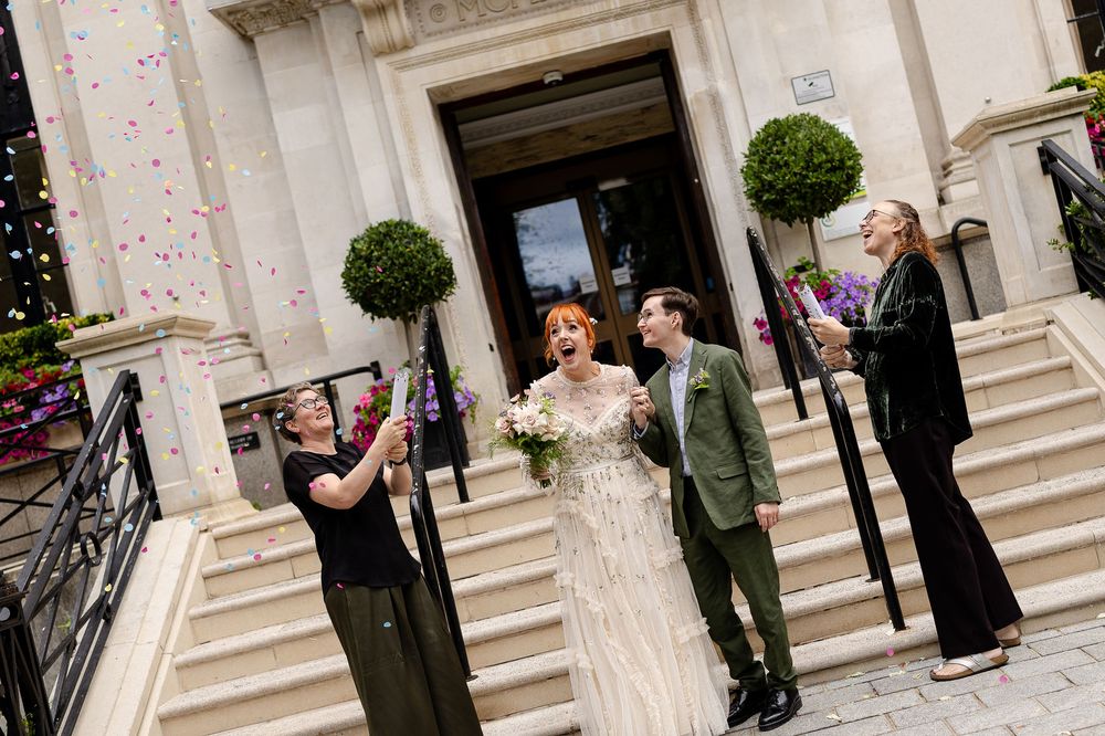 Wedding couple poses together on elegant stone steps of a grand building entrance.